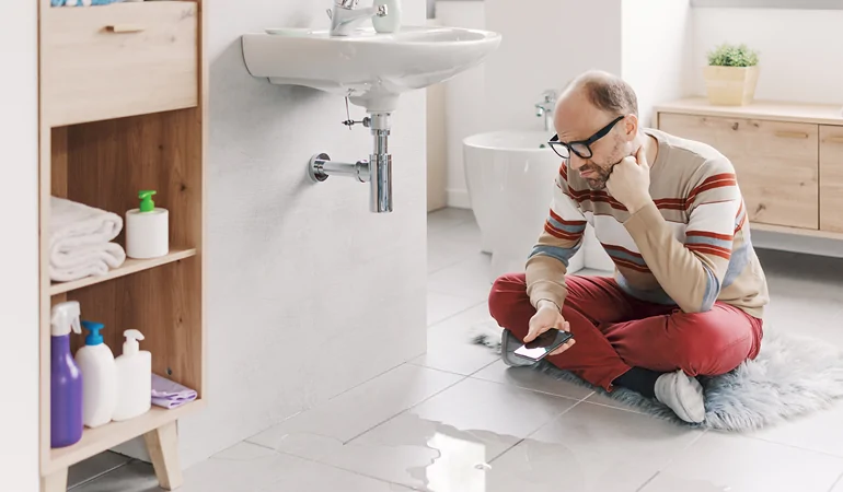 Plumber inspecting bathroom pipes for concealed water leaks